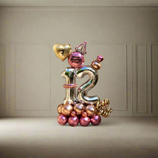 Balloon arrangement with a crown, heart, and metallic pink and gold accents for milestone celebrations.