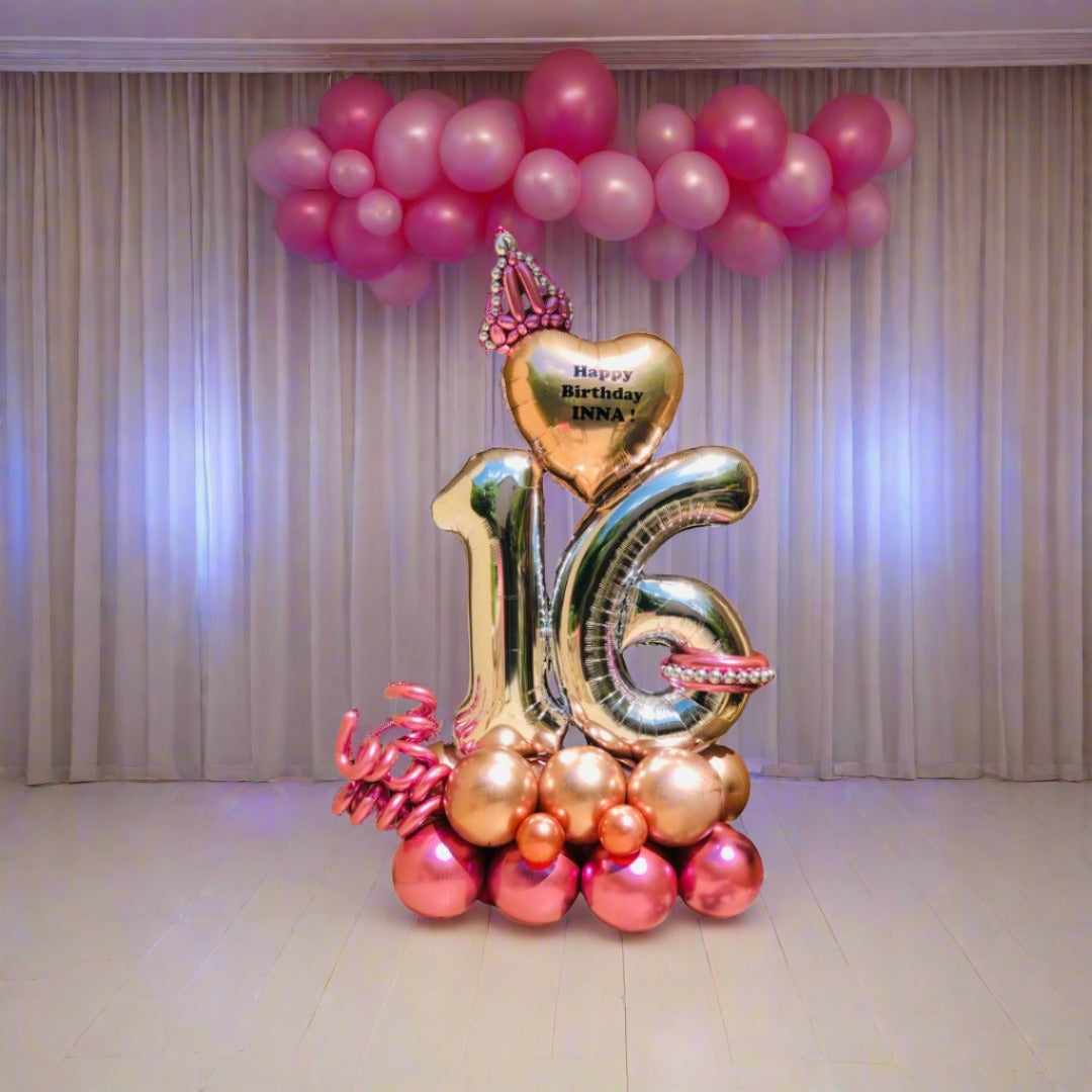 Elegant balloon display featuring a crown, heart, and metallic pink and gold balloons, perfect for birthdays and events.